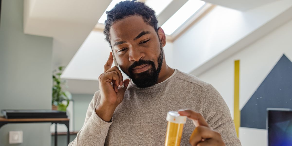 person taking medications at home on the phone with doctor